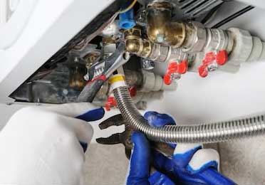 boiler repair, close-up of engineers hands fixing the bottom of the boiler