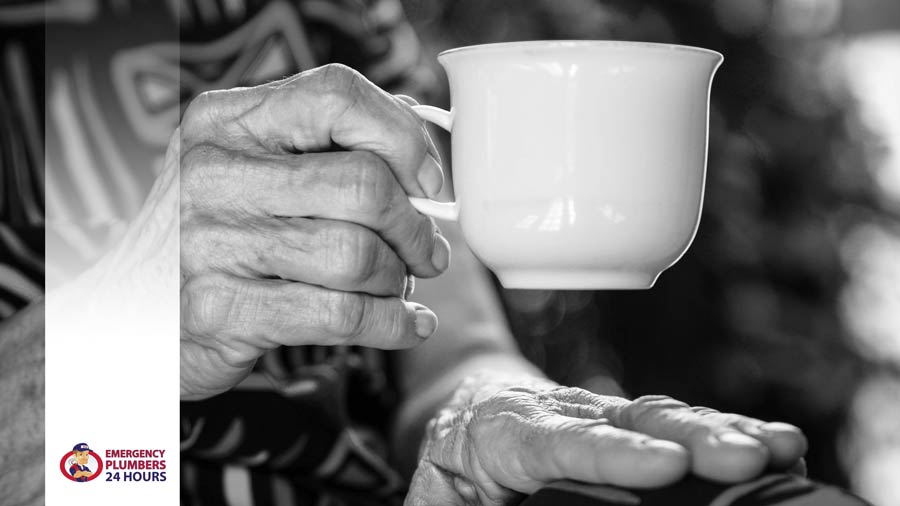 Elderly hand holding a tea cup with emergency plumbers 24 hours logo